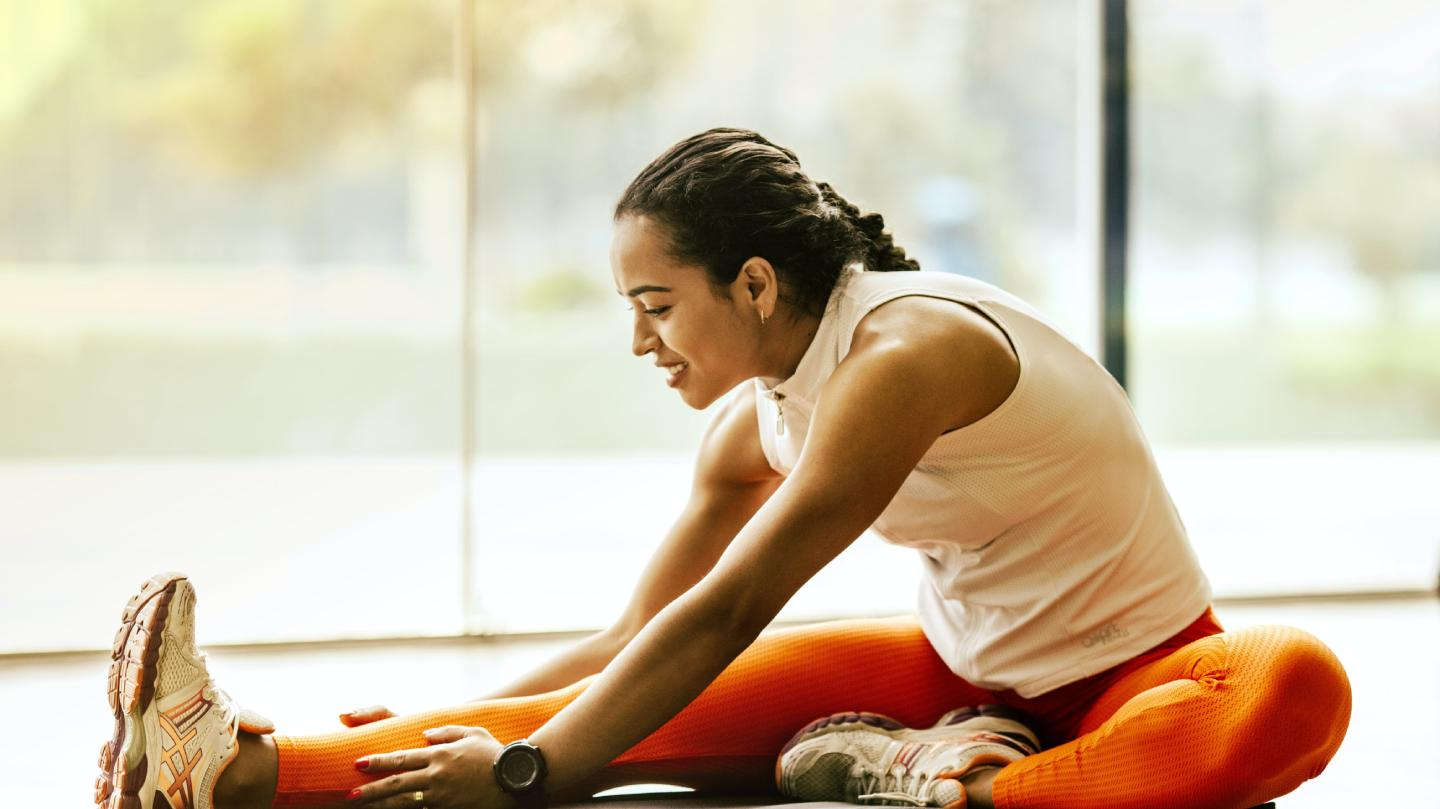 Woman stretching on the floor in a bright gym for peptide and wellness therapy
